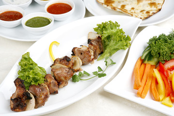 Appetizing shish kebab with tomatoes and greens