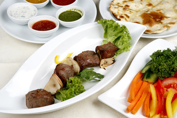 Appetizing shish kebab with tomatoes and greens