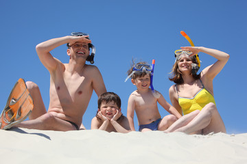 family with snorkeling masks sitting on sand