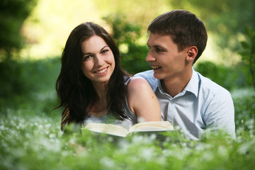 Man and woman sitting on the grass and reading.