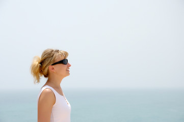 Fototapeta na wymiar Blond girl looking at the blue ocean 2