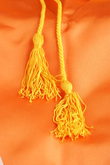 Two hanging graduation tassels on orange silk