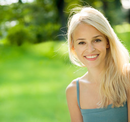 Naklejka premium Portrait of young attractive smiling blond woman, outdoors
