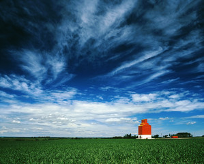 Orange grain elevator against a big blue sky.