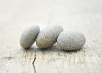 Fototapeta na wymiar three round and soft stones on a old piece of wood