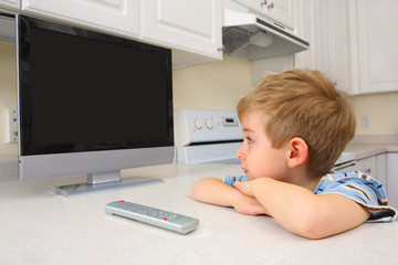 Fototapeta na wymiar Young boy watching tv in a kitchen