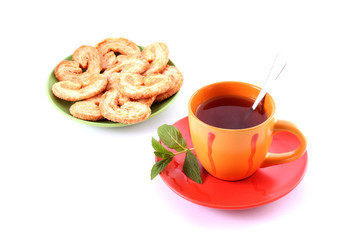 Cup of green tea on the saucer with mint and cookies