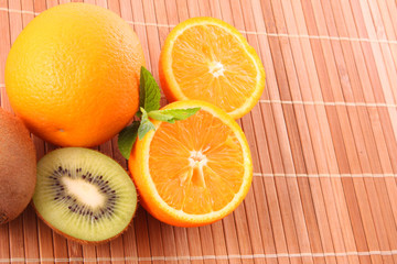 oranges, kiwi  and leaves of mint on brown background