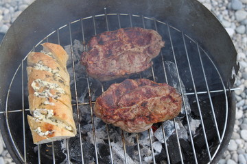 Grillfleisch und Kräuterbaguette auf dem Grill