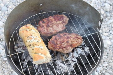 Grillfleisch und Baguette mit Kräuterbutter auf dem Grill