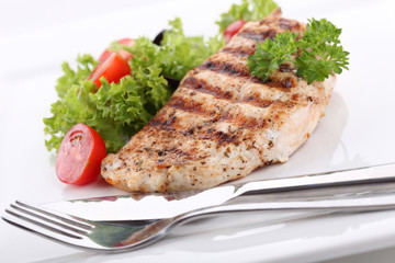 Grilled chicken breasts on a plate with fresh vegetables