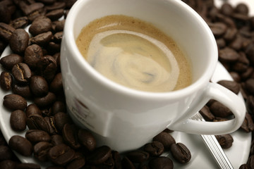 close-up of espresso cup with coffee beans around