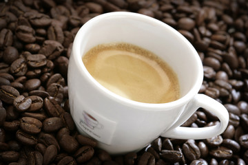 close-up of espresso cup with coffee beans around