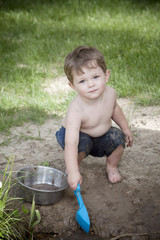 muddy faced little boy with blue shovel