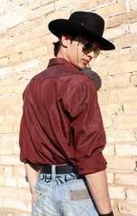 young man posing next to a brick wall