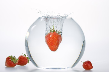 Strawberries falling into a bowl of water