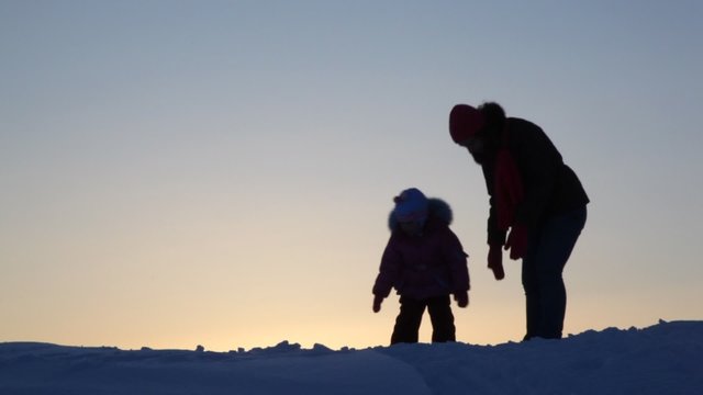 Silhouette mother with child play snow
