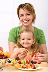 Woman and little girl making fruit kebab