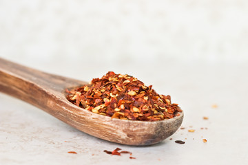 Red hot chilli flakes on a wooden spoon