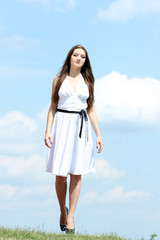 beautiful girl in a white dress on a background of the blue sky