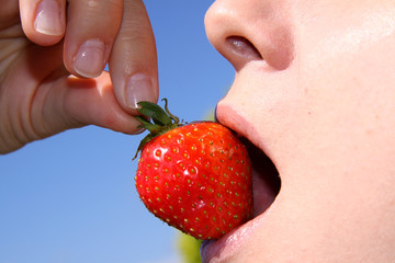 Frau beisst in Erdbeere