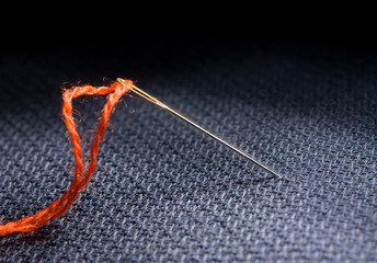 Needle and thread on black fabric