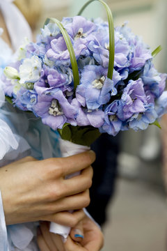 Bride in dress holding beautiful bouquet of Delphinium
