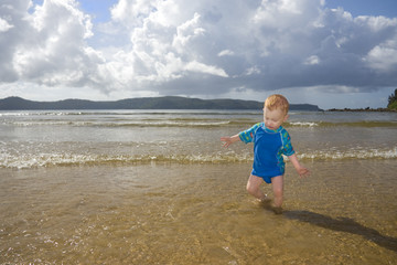 Toddler playing at beach in sunlight with impending storm