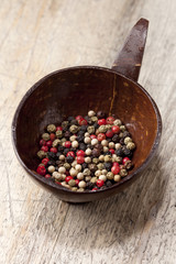 mixed peppercorn in coconut bowl on old wooden table