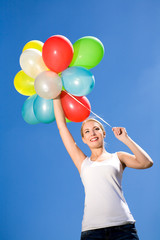 Fototapeta na wymiar Woman holding balloons against blue sky