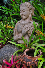 Statue einer Göttin zwischen bunten Pflanzen
