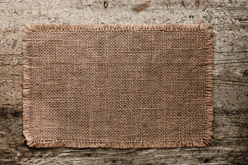 burlap canvas with lacerate edges on old grunge wooden backgroun