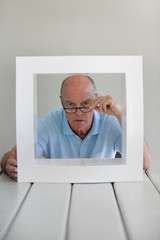 Fototapeta premium Portrait d'un homme senior derrière un cadre blanc