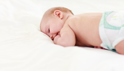 Baby sleeping in bed with his finger in his mouth