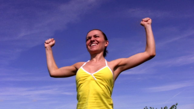 succesful woman jumping and throwing her hands in the air