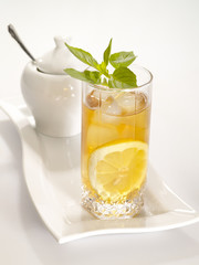 Cold black tea with lemon, ice and water drops on the glass surf