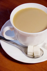 Coffee cup with white coffee and cubes of sugar