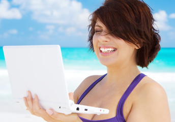 woman with laptop computer on the beach