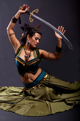 Fototapeta na wymiar Attractive bellydancer in tribal costume and holding sword