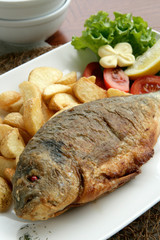 Grilled fish served with potato wedges