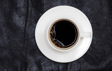 espresso coffee in white cup directly above, black leather back