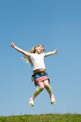 Little girl jumping against beautiful sky