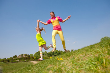 Fototapeta premium Two girls jumping on green meadow