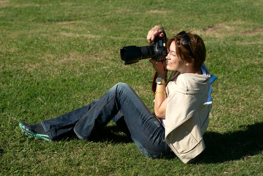 professional woman photographer in park on a gras