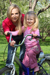 Obraz premium Mother with daughter on bicycle in spring garden