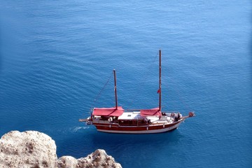 Chilliges Foto: Das Blaues Meer mit Zweimaster aus der Vogelperspektive. Ruhiges blaues Wasser, weißer Fels und ein Segelschiff auf Kurs.