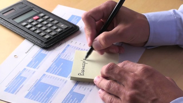 jungunternehmer notiert "business-plan" auf einen notizzettel