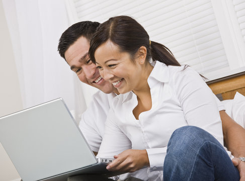 Happy Couple Sitting Together and Looking at a Laptop