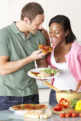 Young Couple Eating Meal In Kitchen