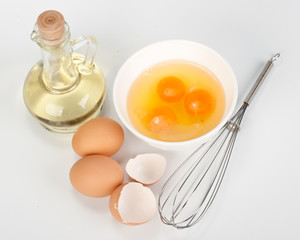 Fototapeta na wymiar Eggs, oil and whisk